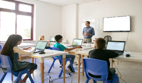An image of a teacher and students in class using laptops