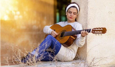  Woman in white sited on a window playing a guitar