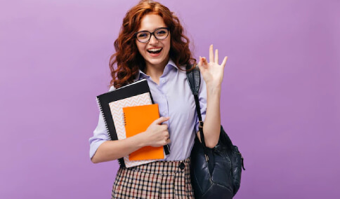 Red Haired Lady in Eyeglasses Holds Books and Shows OK Sign